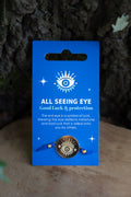 Pulsera All Seeing Eye con meda llón dorado y cordón azul sobre tarjeta coleccionable