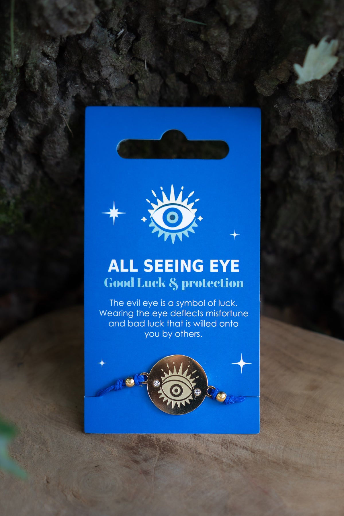 Pulsera All Seeing Eye con meda llón dorado y cordón azul sobre tarjeta coleccionable