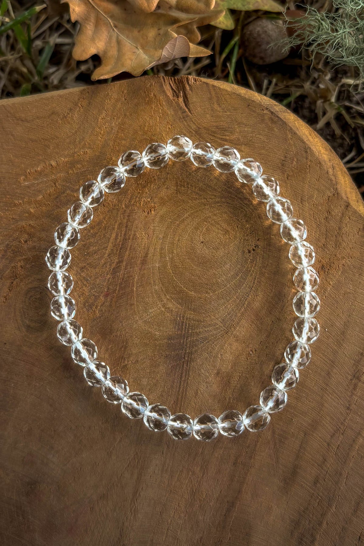 Pulsera de cuarzo cristal transparente con cuentas facetadas de 6mm sobre madera natural