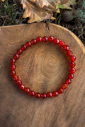 Pulsera de cornalina natural con cuentas facetadas de 6mm en tono rojo anaranjado sobre madera natural