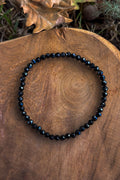 Pulsera de turmalina negra natural con cuentas facetadas de 4mm con destellos azulados sobre madera natural