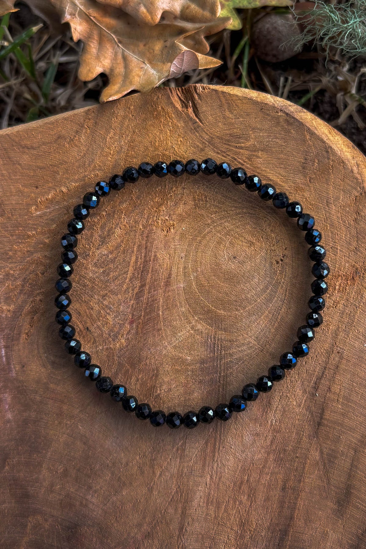 Pulsera de turmalina negra natural con cuentas facetadas de 4mm con destellos azulados sobre madera natural