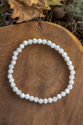 Pulsera de piedra luna natural con cuentas facetadas de 4mm en blanco nacarado con reflejos iridiscentes sobre madera natural