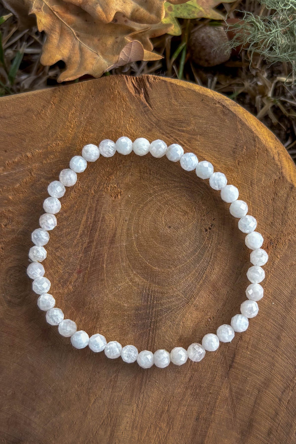 Pulsera de piedra luna natural con cuentas facetadas de 4mm en blanco nacarado con reflejos iridiscentes sobre madera natural