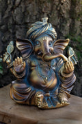 Figura de Ganesha sentada con turbante, tonos dorados y oscuros y matices azulados