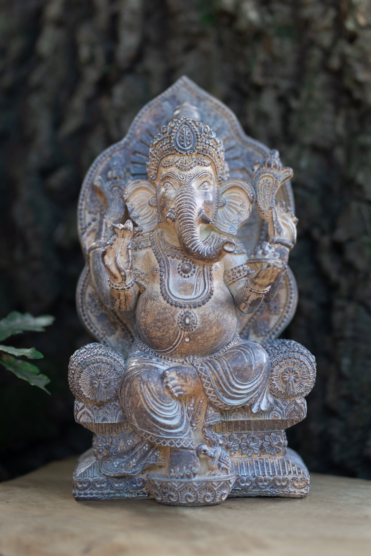 Figura de Ganesha en tonos plateados sentada en un trono con respaldo ornamentado