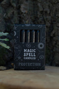Caja Magic Spell Candles Protection con velas negras y decoración de símbolos celestes.