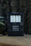 Velas blancas en caja negra Magic Spell Candles decorada con símbolos celestes.