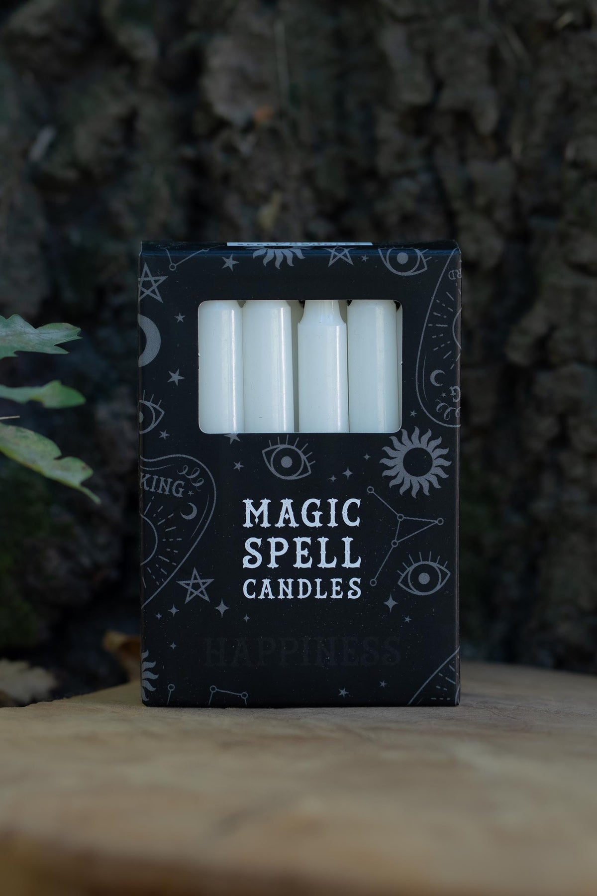 Velas blancas en caja negra Magic Spell Candles decorada con símbolos celestes.