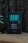 Caja negra Magic Spell Candles Luck con velas verdes y símbolos celestes.
