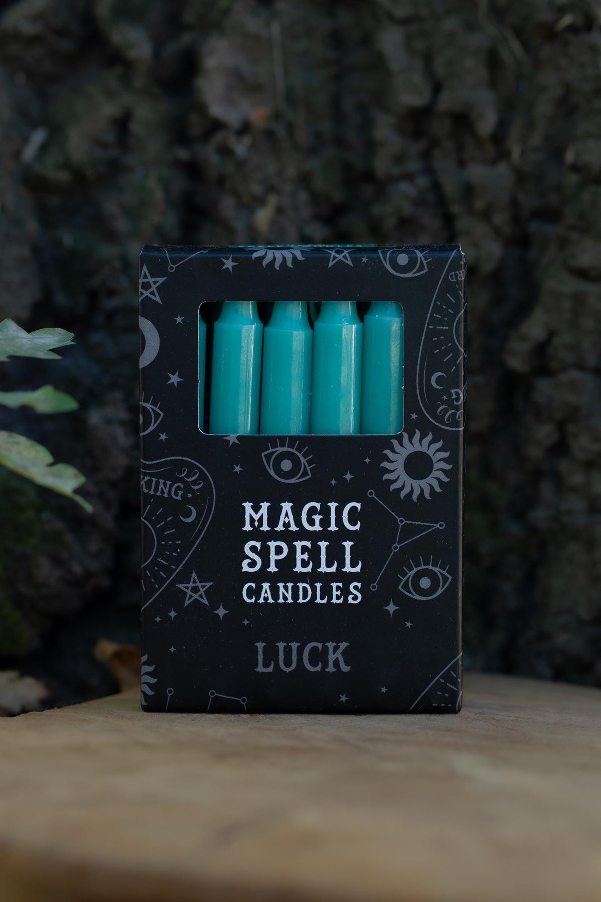 Caja negra Magic Spell Candles Luck con velas verdes y símbolos celestes.