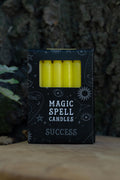 Caja negra Magic Spell Candles Success con velas amarillas y símbolos celestes.