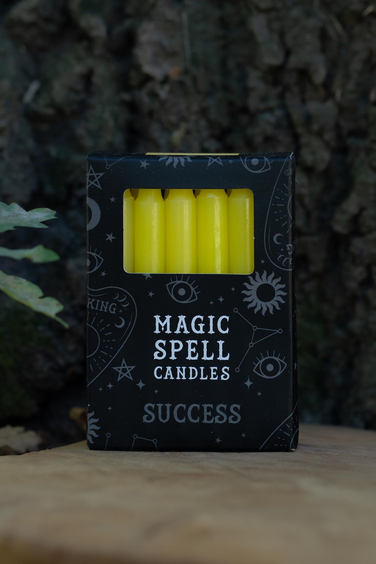 Caja negra Magic Spell Candles Success con velas amarillas y símbolos celestes.