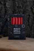 Caja negra Magic Spell Candles Love con velas rojas y símbolos celestes.