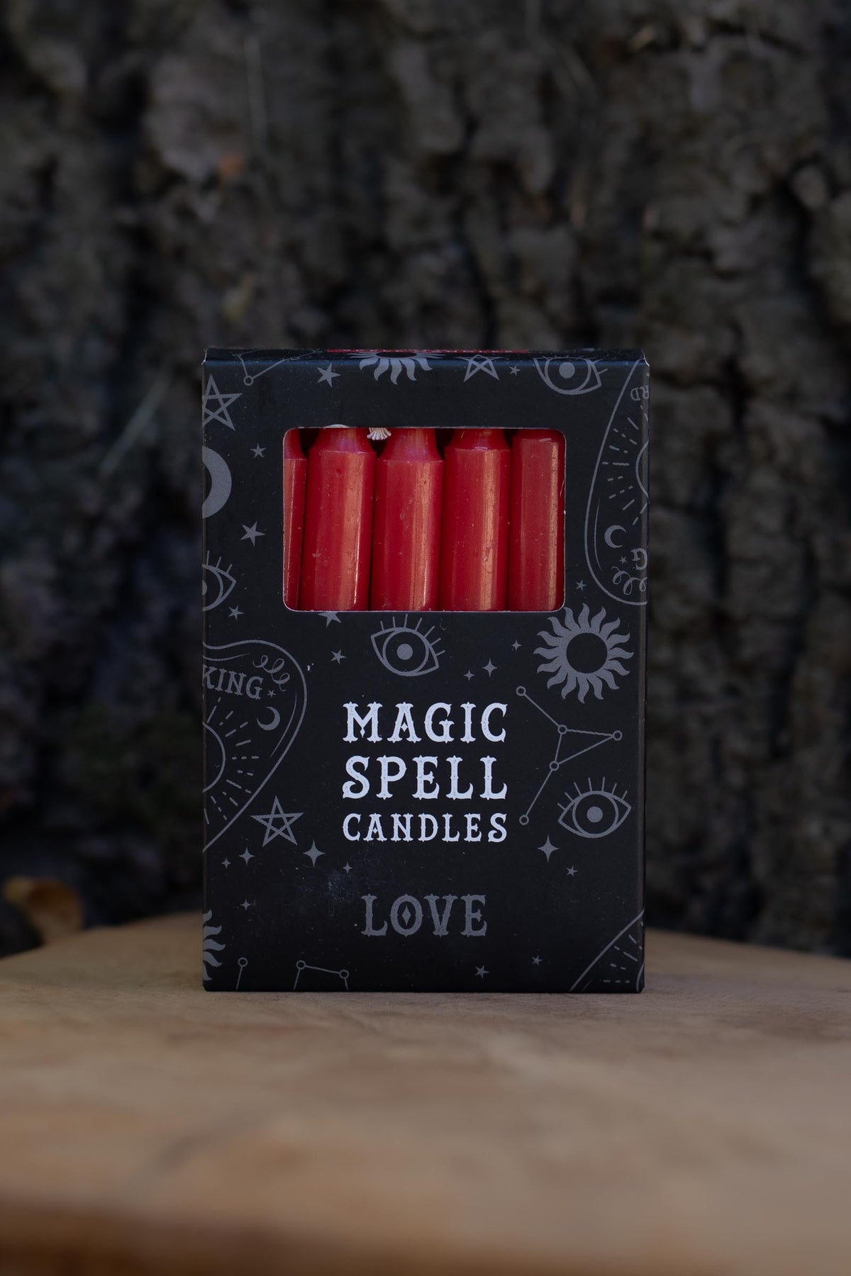 Caja negra Magic Spell Candles Love con velas rojas y símbolos celestes.