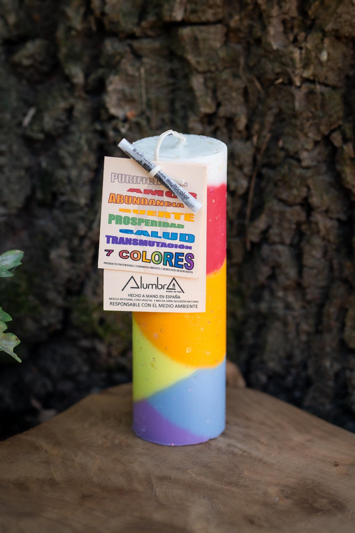 Velón cilíndrico de siete colores con franjas multicolor y etiqueta frontal