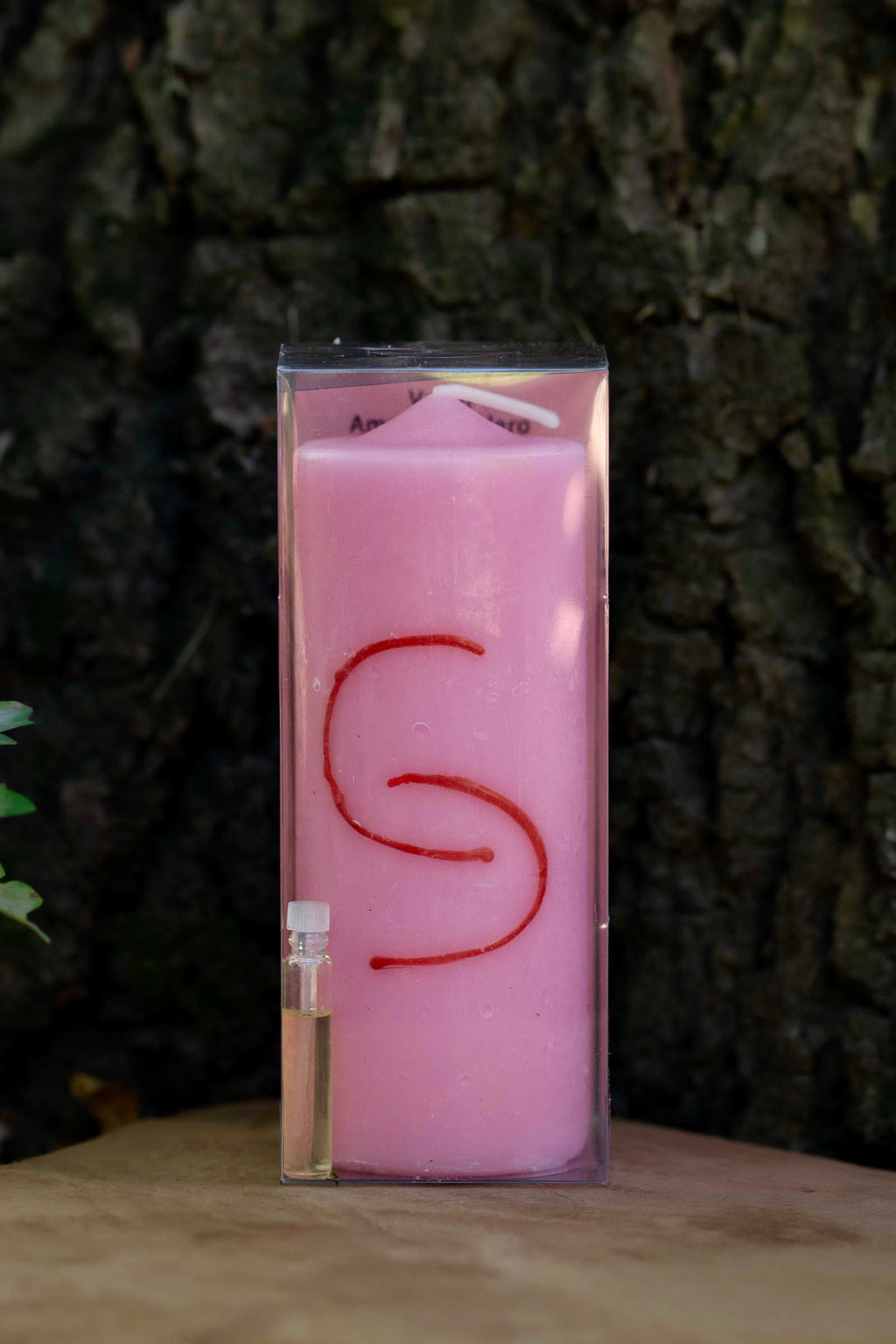 Velón rosa Amor Verdadero Doble Carga con motivo rojo entrelazado y pequeño frasco.