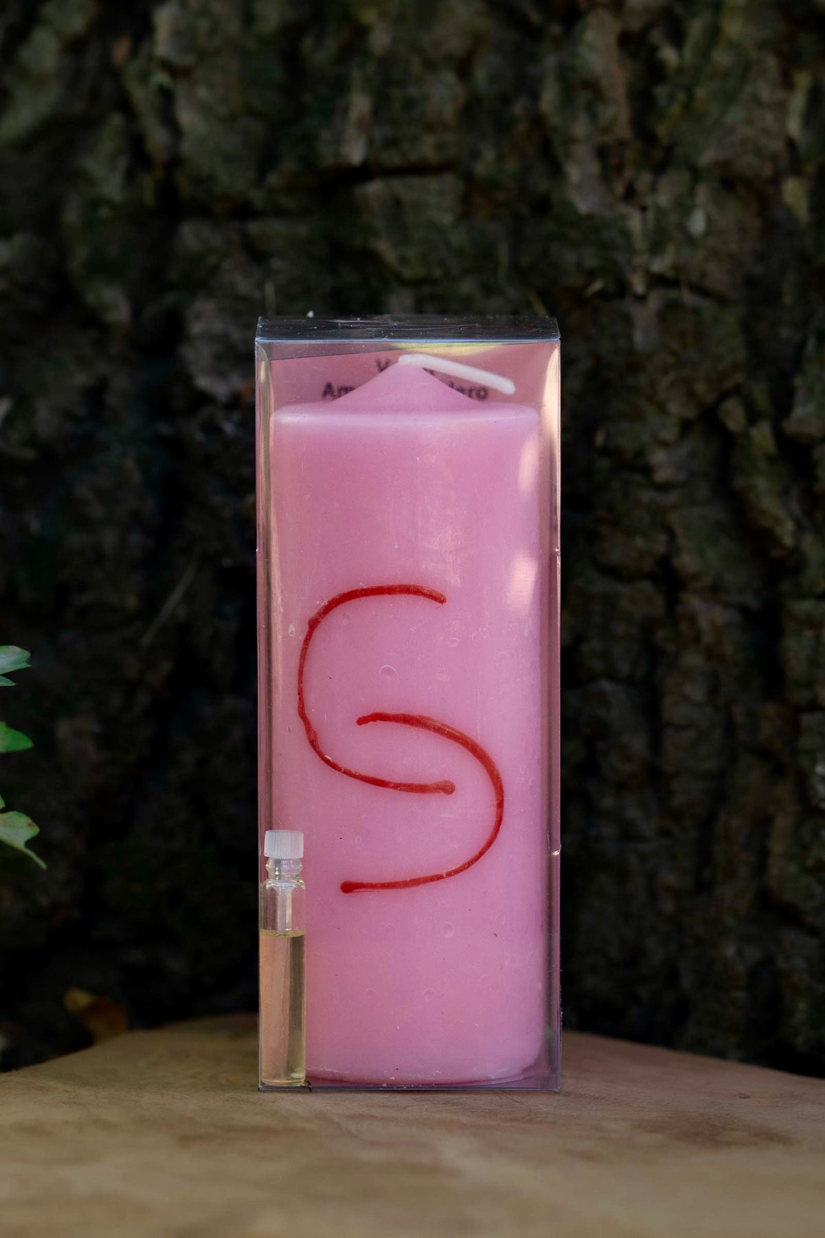 Velón rosa Amor Verdadero Doble Carga con motivo rojo entrelazado y pequeño frasco.