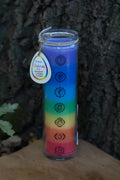 Vela aromática de siete capas de colores en recipiente transparente con los símbolos de los siete chakras.