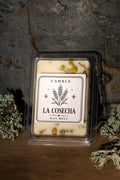 La Cosecha Wax Melt de Cambla con flores de manzanilla visibles en cera blanca, packaging transparente sobre madera con musgo