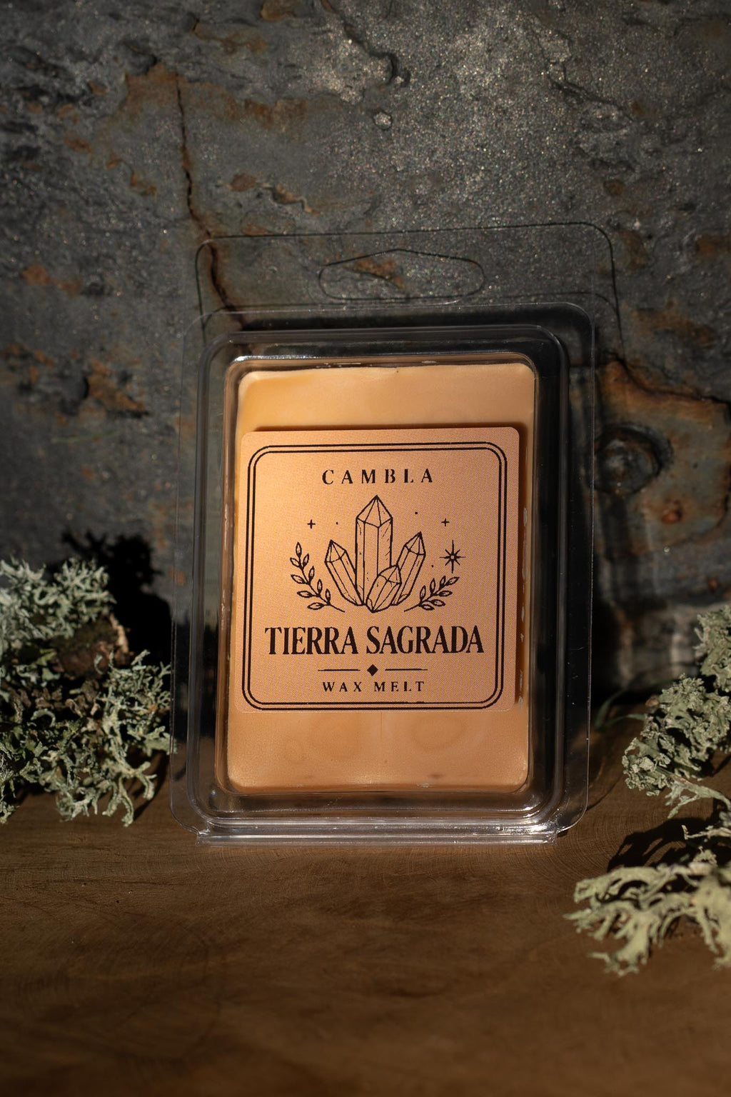 Tierra Sagrada Wax Melt de Cambla en packaging transparente dorado sobre madera con musgo